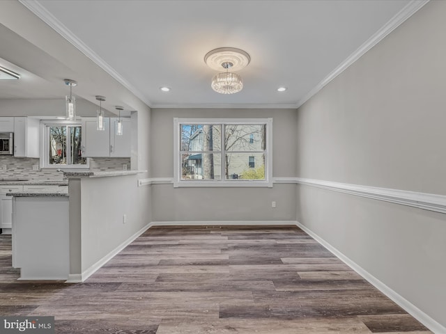 unfurnished dining area with crown molding, wood-type flooring, and a chandelier