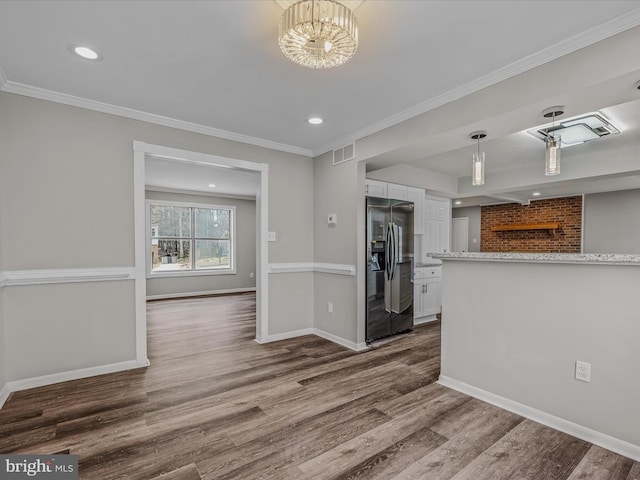 kitchen with crown molding, stainless steel fridge, an inviting chandelier, hardwood / wood-style floors, and white cabinets