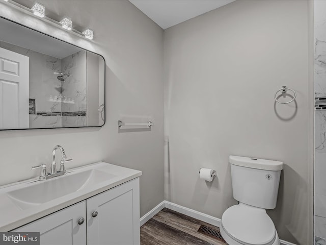 bathroom with hardwood / wood-style flooring, vanity, walk in shower, and toilet