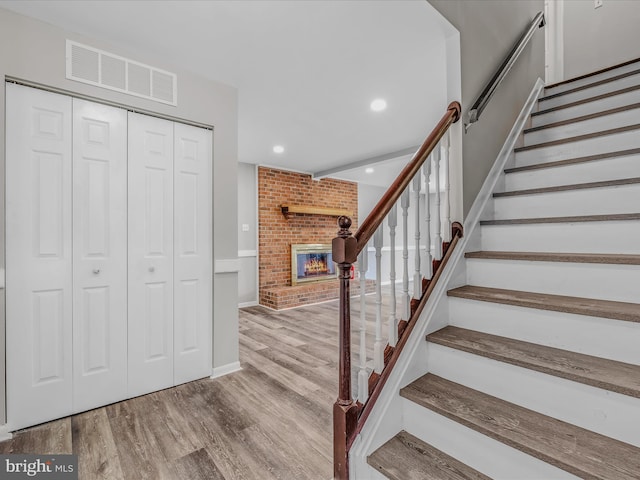 stairs with a fireplace and hardwood / wood-style floors