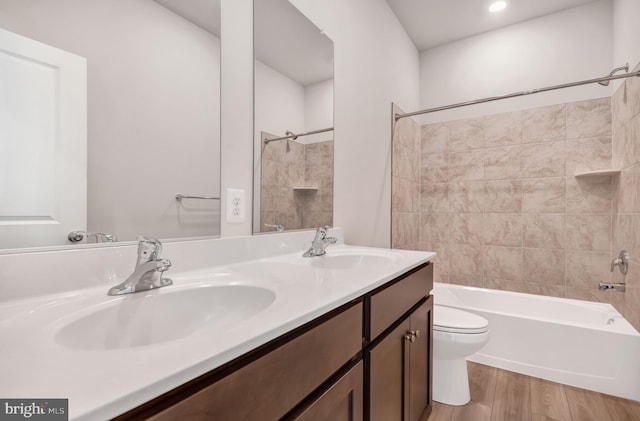 full bathroom featuring tiled shower / bath combo, wood-type flooring, vanity, and toilet