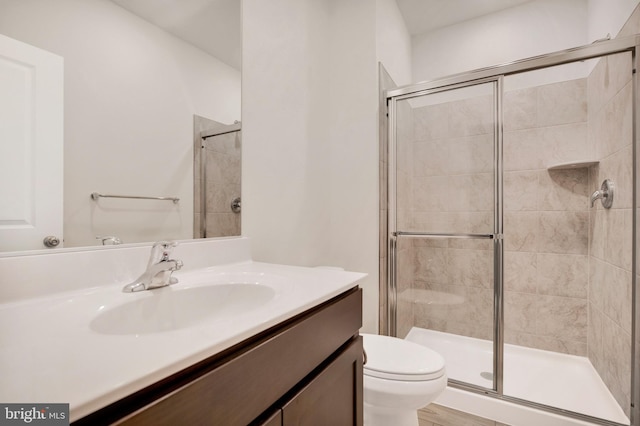 bathroom featuring toilet, vanity, and walk in shower