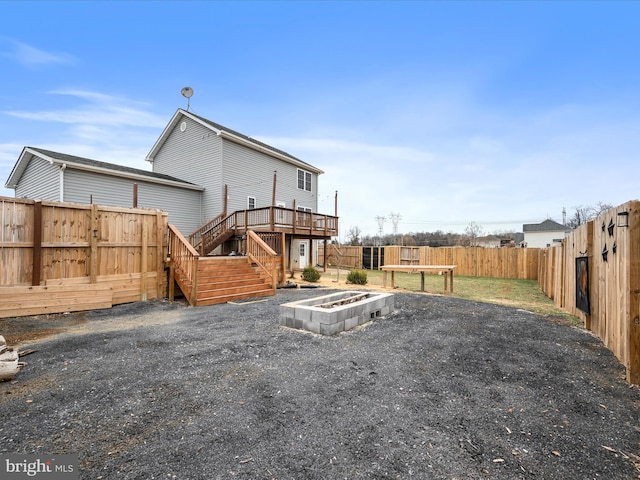 back of property with a wooden deck and a fire pit