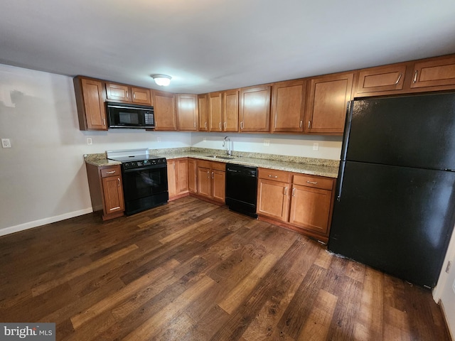 kitchen with sink, light stone counters, dark hardwood / wood-style flooring, and black appliances