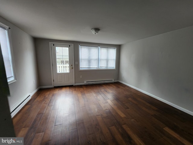 spare room with a baseboard heating unit and dark hardwood / wood-style flooring