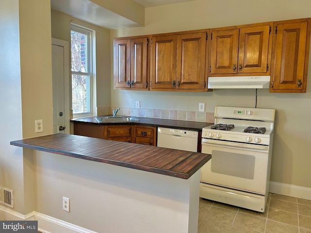 kitchen with light tile patterned flooring, sink, wooden counters, kitchen peninsula, and white appliances