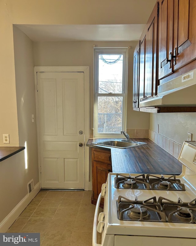 kitchen with sink, light tile patterned floors, and gas range gas stove