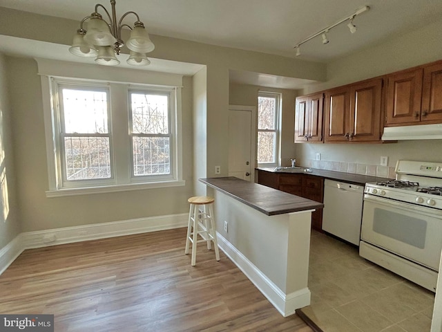 kitchen with pendant lighting, sink, white appliances, and a wealth of natural light