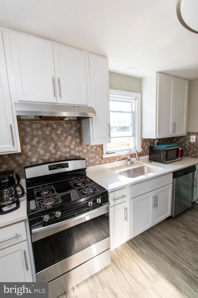 kitchen with sink, white cabinetry, stainless steel appliances, light hardwood / wood-style floors, and backsplash