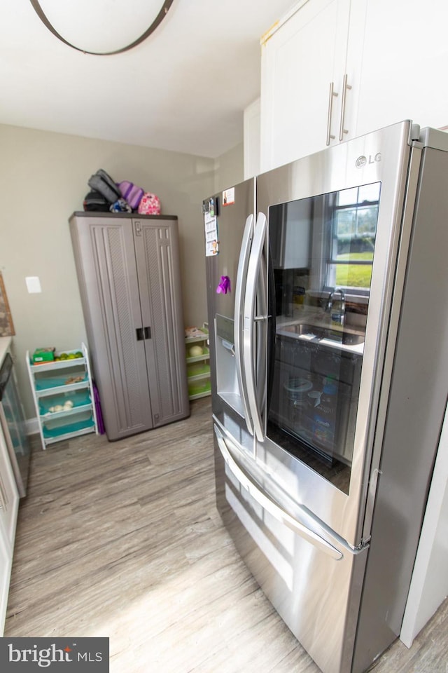 kitchen featuring stainless steel refrigerator, white cabinetry, and light hardwood / wood-style floors