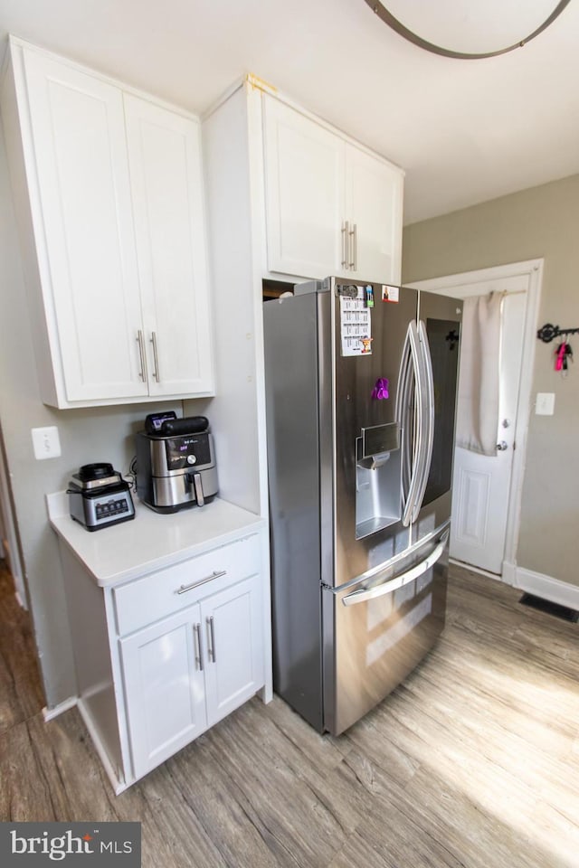 kitchen featuring white cabinetry, stainless steel fridge with ice dispenser, and light wood-type flooring