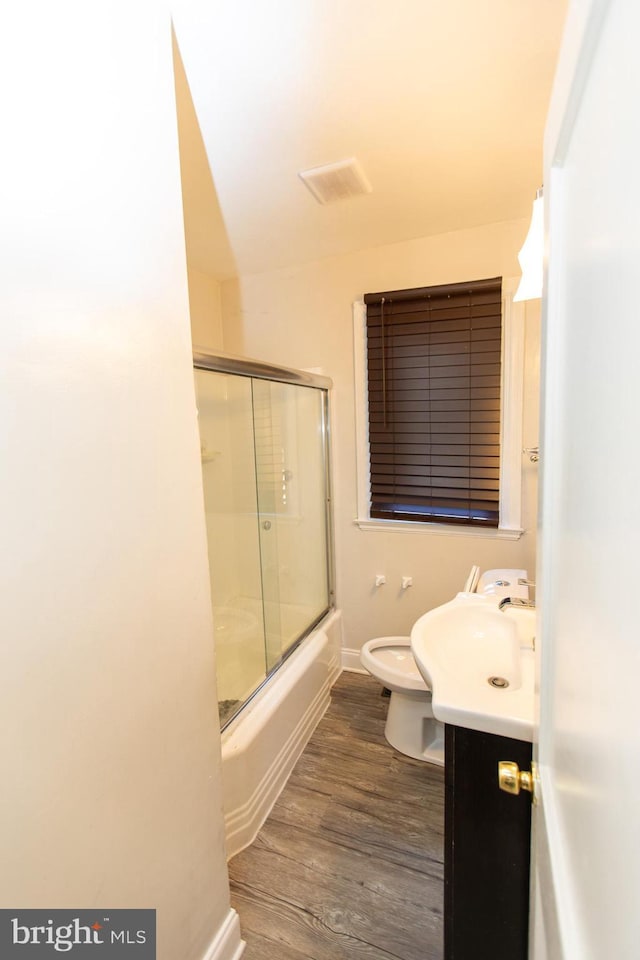 full bathroom with vanity, hardwood / wood-style flooring, enclosed tub / shower combo, and toilet