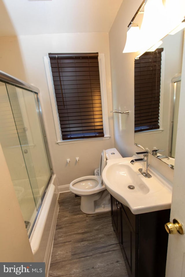 full bathroom with enclosed tub / shower combo, wood-type flooring, toilet, and vanity