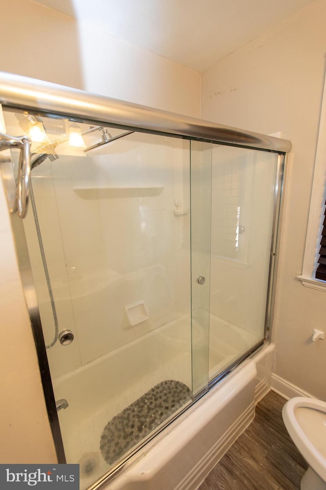 bathroom with bath / shower combo with glass door, toilet, and wood-type flooring