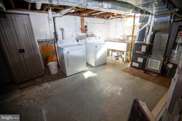 basement with washing machine and clothes dryer, sink, and gas water heater