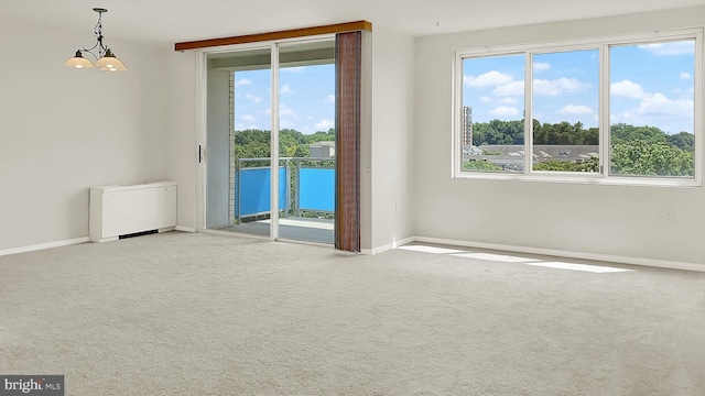 spare room featuring a notable chandelier, plenty of natural light, and light colored carpet