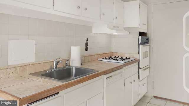 kitchen with sink, tile counters, white cabinets, white appliances, and backsplash