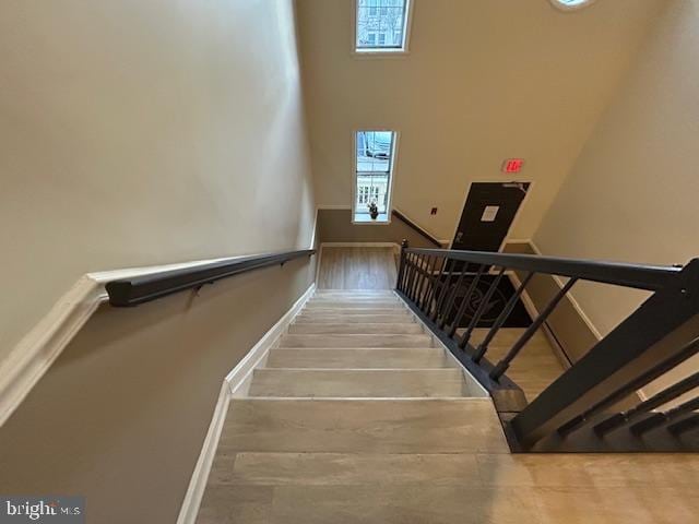 stairs with hardwood / wood-style flooring and a high ceiling