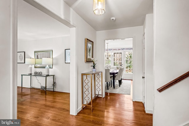 hallway with hardwood / wood-style flooring and a notable chandelier