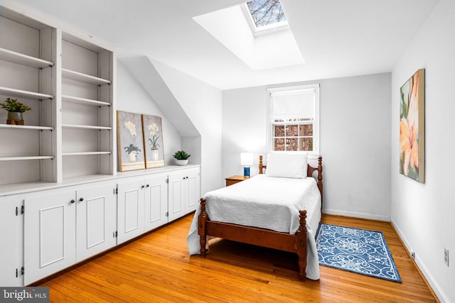 bedroom featuring lofted ceiling with skylight and light wood-type flooring