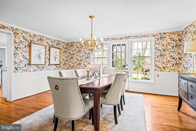 dining space featuring an inviting chandelier, ornamental molding, and light wood-type flooring