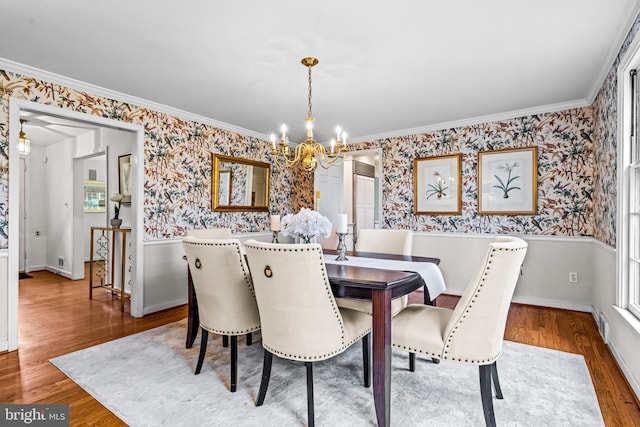 dining room with an inviting chandelier, ornamental molding, and wood-type flooring