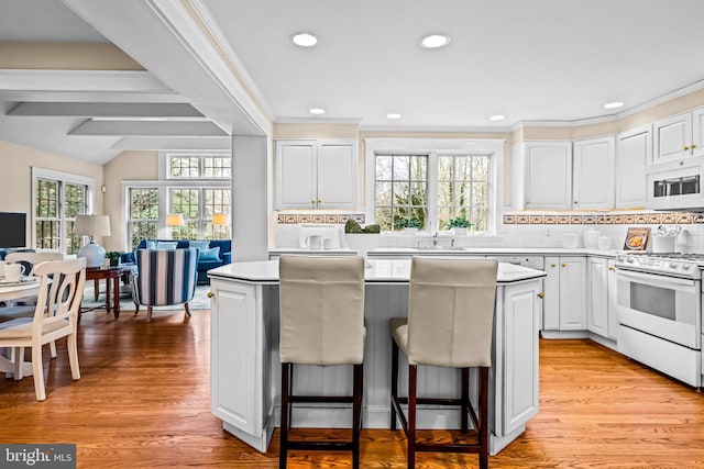 kitchen featuring white cabinetry, white appliances, light wood-type flooring, and a kitchen island