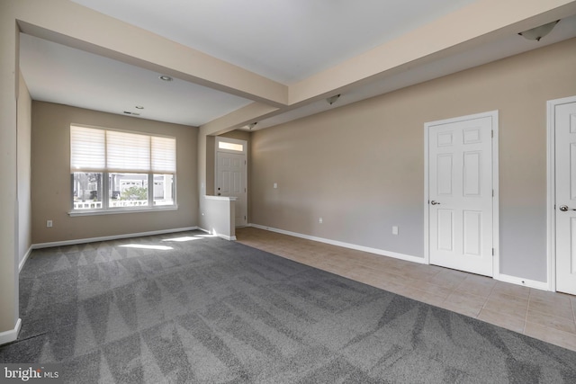 spare room featuring beamed ceiling and tile patterned floors