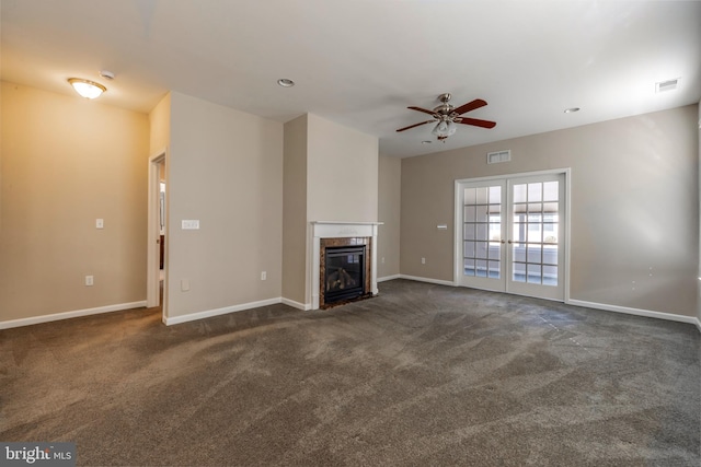 unfurnished living room with dark carpet, a high end fireplace, french doors, and ceiling fan