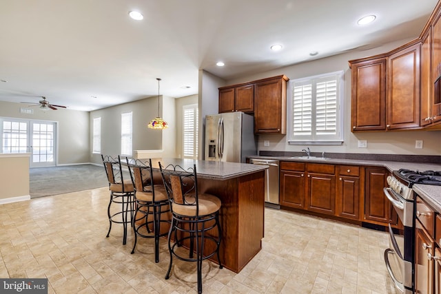 kitchen with sink, a breakfast bar area, a center island, pendant lighting, and stainless steel appliances