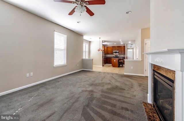 unfurnished living room featuring light colored carpet and ceiling fan