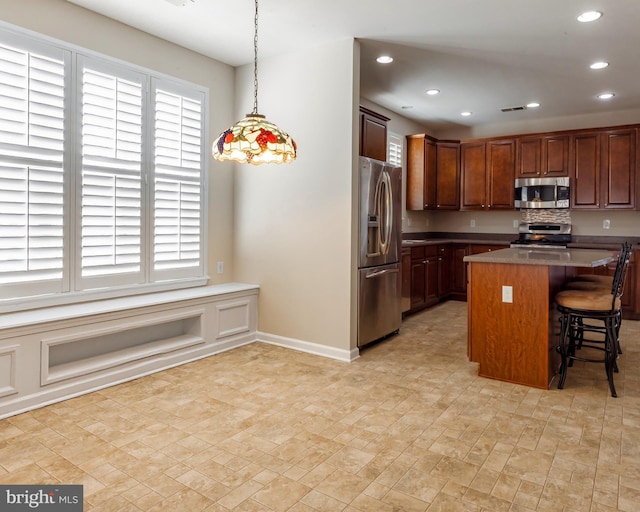 kitchen featuring a kitchen island, appliances with stainless steel finishes, hanging light fixtures, and a kitchen breakfast bar