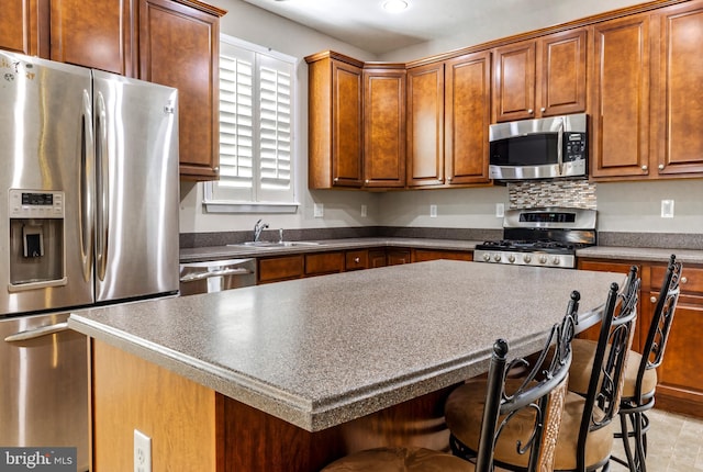 kitchen with stainless steel appliances, a kitchen island, a breakfast bar, and sink