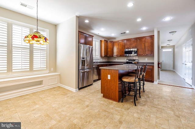 kitchen featuring a kitchen island, appliances with stainless steel finishes, a breakfast bar, and pendant lighting