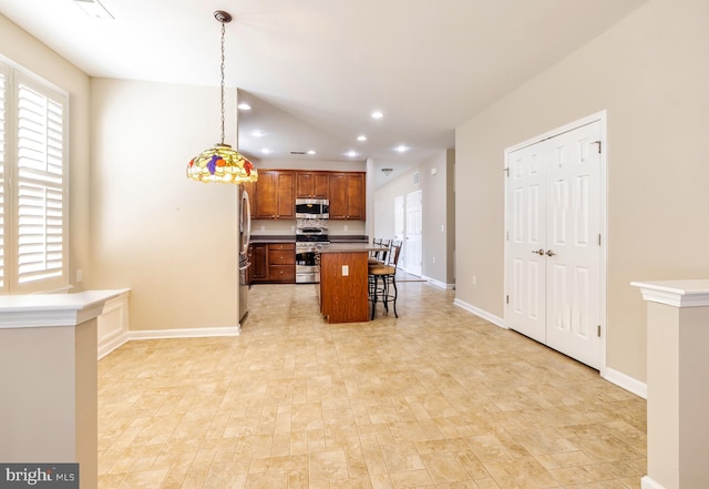 kitchen featuring a breakfast bar area, stainless steel appliances, a wealth of natural light, a kitchen island, and decorative light fixtures