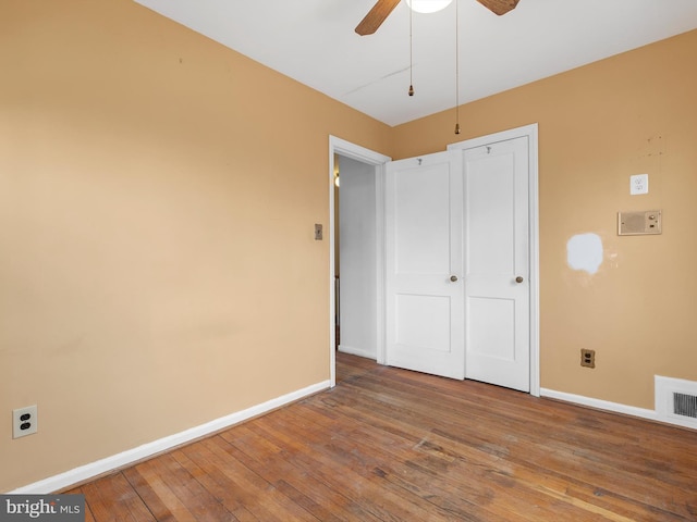 unfurnished bedroom with ceiling fan, hardwood / wood-style floors, visible vents, and baseboards