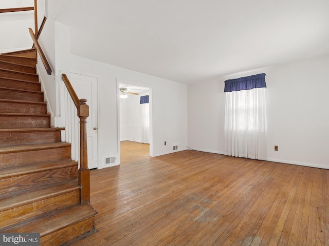 unfurnished room with stairs, wood-type flooring, and visible vents