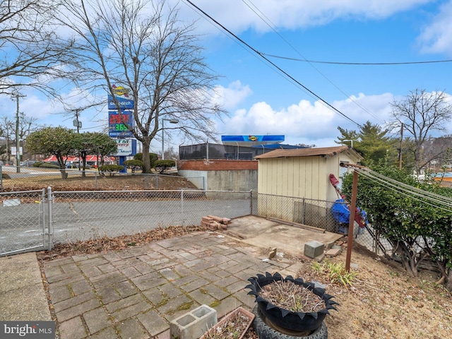 view of patio featuring an outbuilding, a storage unit, fence, and a gate