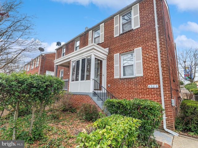 multi unit property featuring brick siding and a sunroom