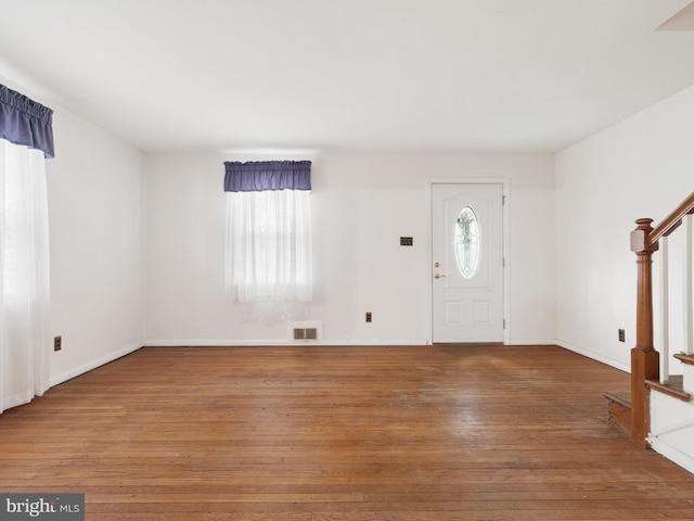 foyer with visible vents, stairway, baseboards, and wood finished floors