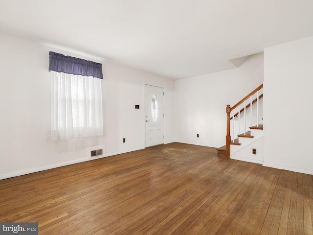 foyer entrance featuring a wealth of natural light, visible vents, stairway, and hardwood / wood-style floors