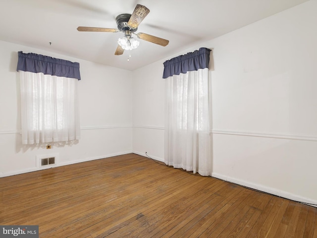 unfurnished room with ceiling fan, hardwood / wood-style floors, visible vents, and baseboards