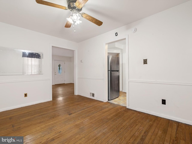 spare room featuring a ceiling fan, wood-type flooring, visible vents, and baseboards