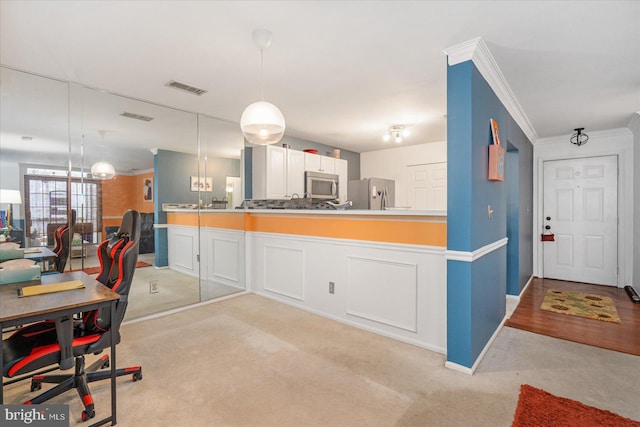 kitchen featuring stainless steel appliances, white cabinetry, pendant lighting, and light colored carpet