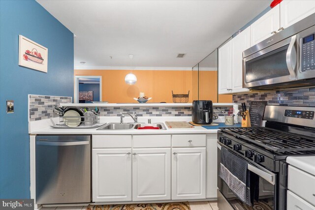 kitchen featuring sink, appliances with stainless steel finishes, white cabinetry, hanging light fixtures, and backsplash