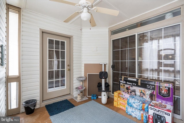 interior space featuring ceiling fan and wooden walls