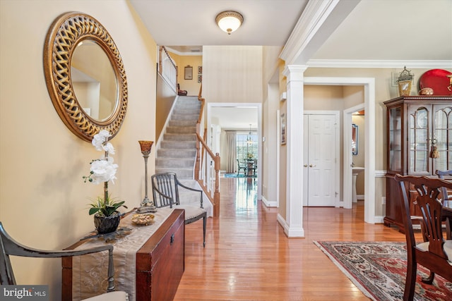 entrance foyer featuring ornate columns, ornamental molding, and light hardwood / wood-style flooring