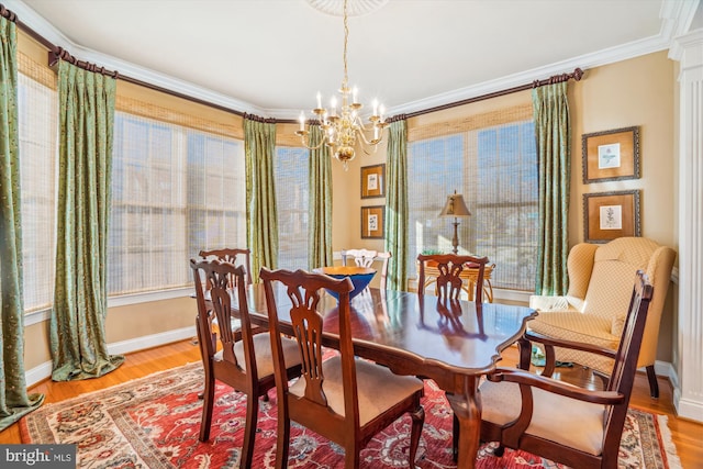 dining room with crown molding, a healthy amount of sunlight, light hardwood / wood-style flooring, and a notable chandelier