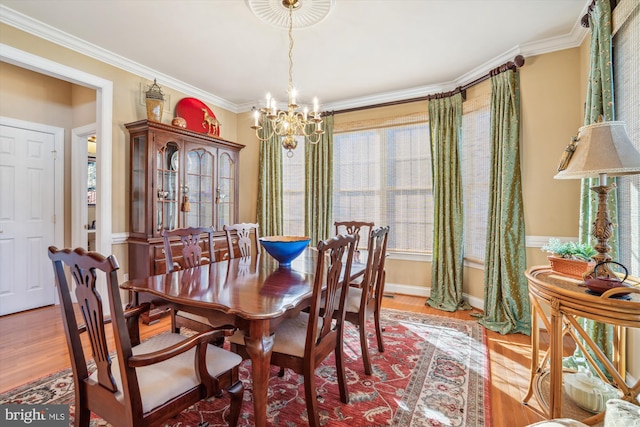 dining room with ornamental molding, wood-type flooring, and a notable chandelier