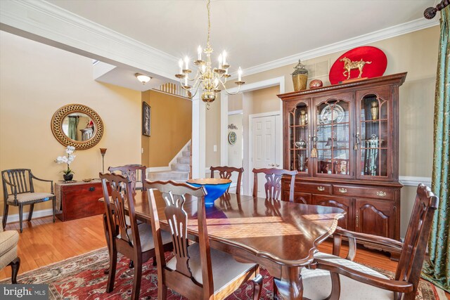 dining space with a notable chandelier, ornamental molding, and light wood-type flooring